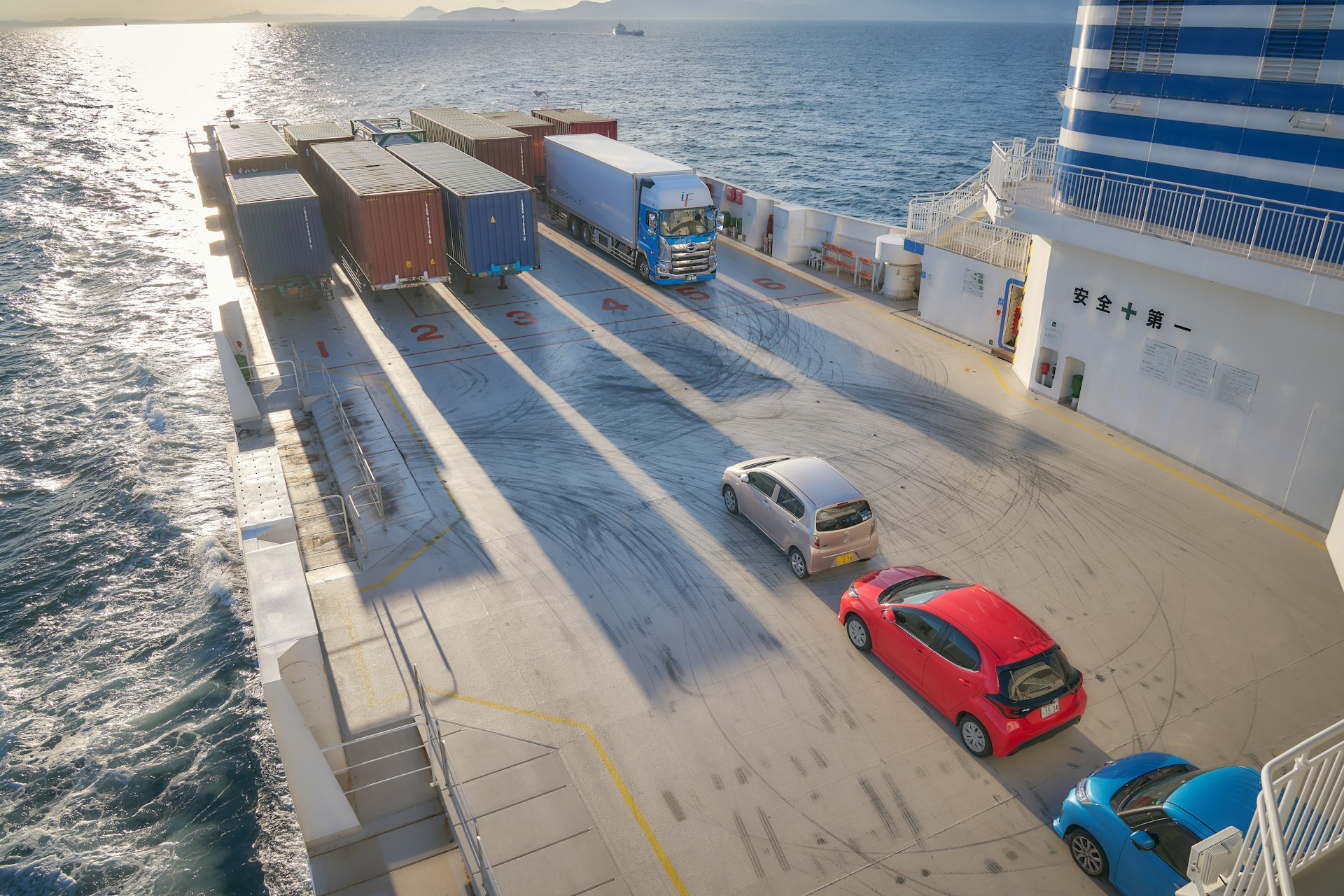 A red car is parked on the side of a ferry
